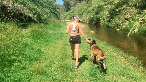 Mujer paseando con su perro sin tirones junto al río