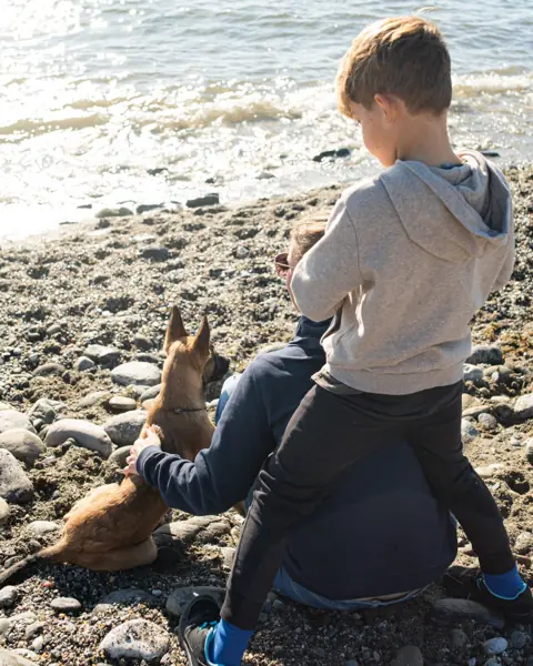 Niño y perro sentados juntos en la playa de Estepona